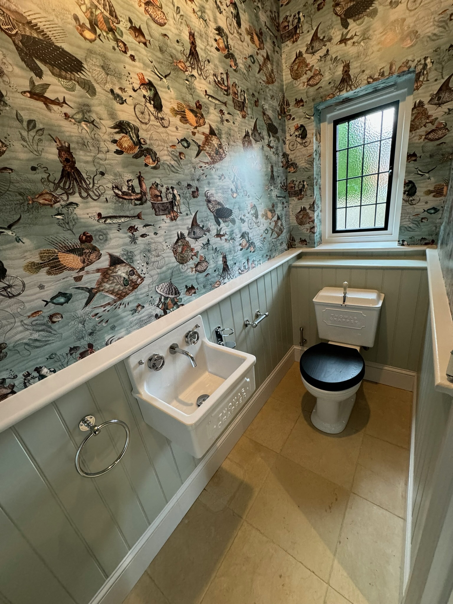 A characterful downstairs cloakroom — panelling, basin and pipework run neatly.