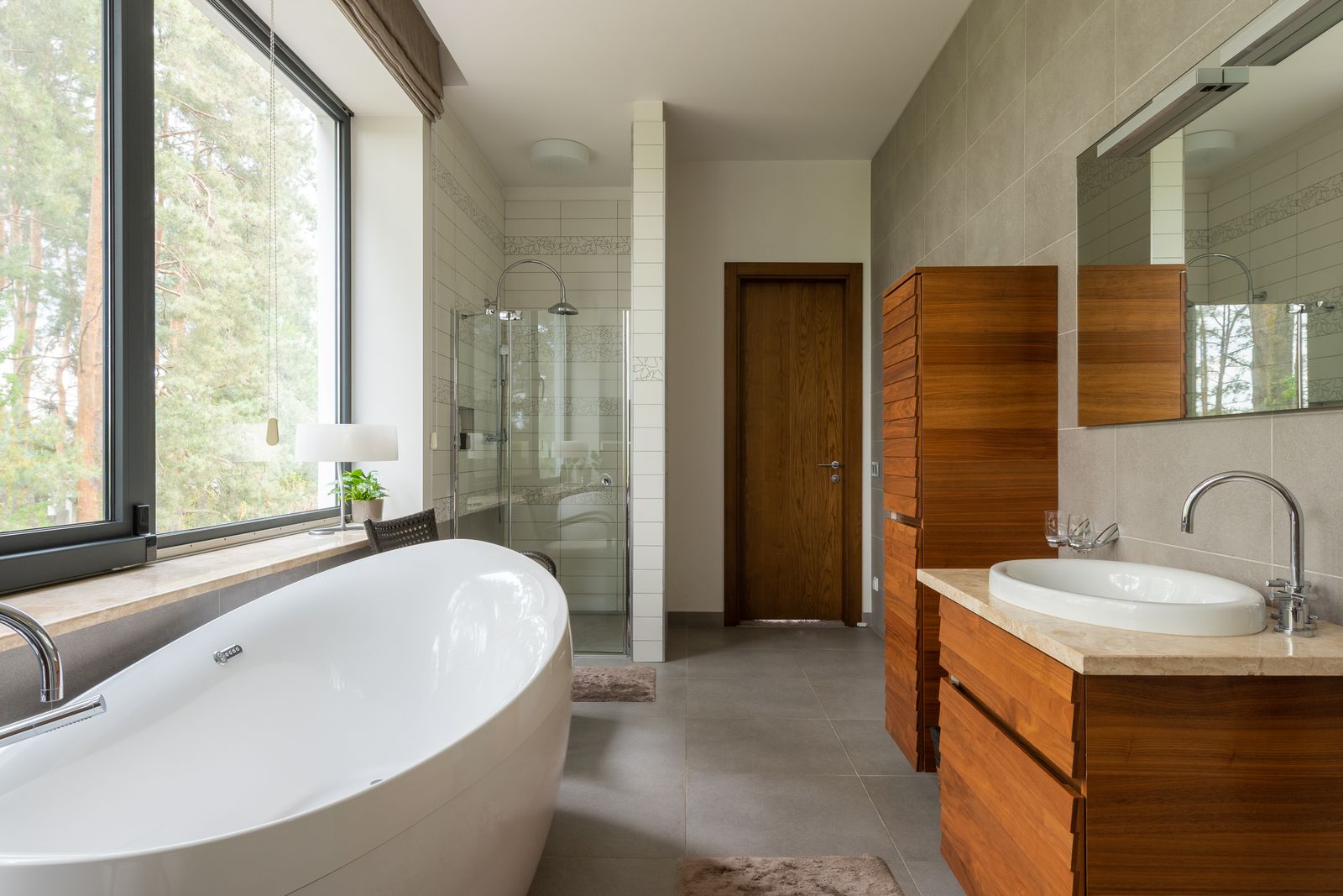 A finished modern bathroom with a freestanding bath and walnut vanity